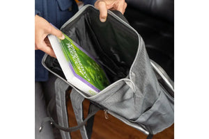 Someone putting a Modern Essentials hardcover book into the doTERRA backpack's main pocket.