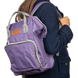 A woman wearing the doTERRA Wellness Advocate Branded Backpack in a purple with olive green accent color.