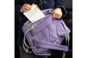 A woman sliding handouts into the back zipper pocket of the doTERRA Branded Backpack.