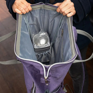Someone holding open the doTERRA Branded backpack showing how a diffuser fits in the size compartment inside the main pocket.