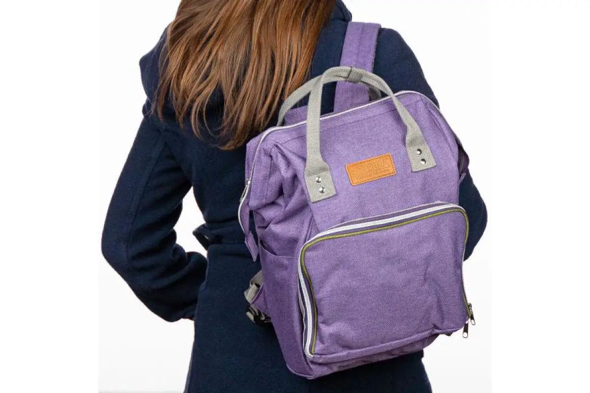 A woman wearing the doTERRA Wellness Advocate Branded Backpack in a graphite, gray color.