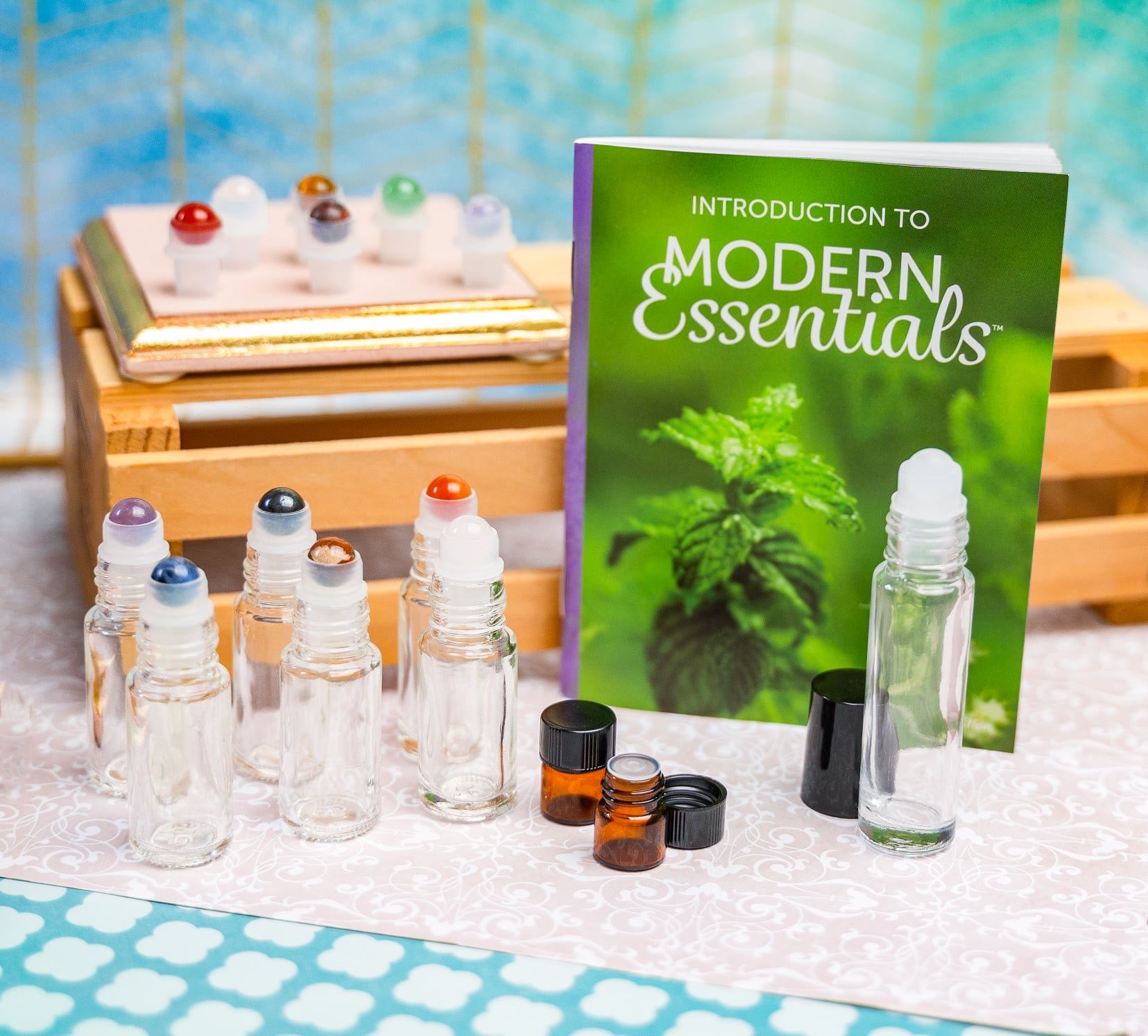 An "Introduction to Modern Essentials" booklet (11th Edition) with gemstone roller bottles and sample vials.