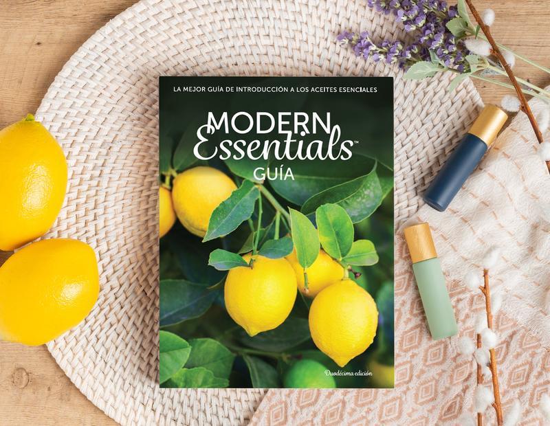 Our Modern Essentials Handbook in Spanish with a wicker placemat, lemons, roller bottles, and some plants.