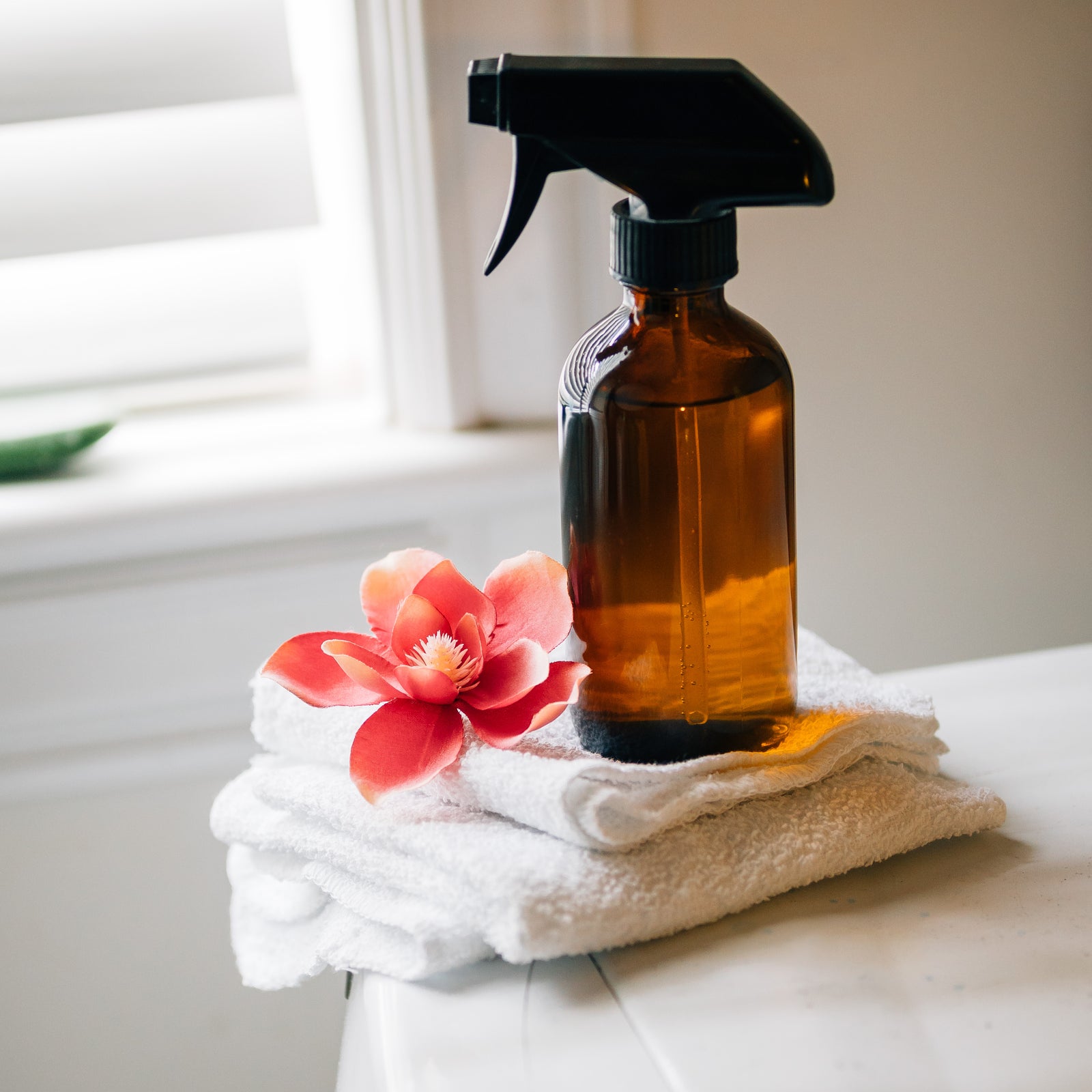 An 8 oz. amber glass trigger spray bottle sitting on some towels on a washing machine. 