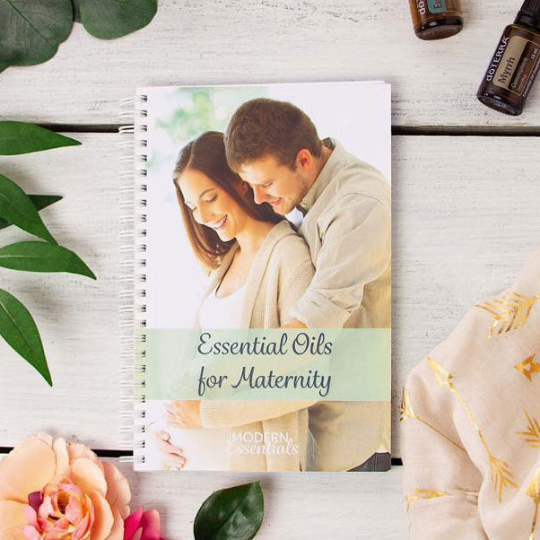 Essential Oils for Maternity (3rd Edition) with essential oil vials and flowers.
