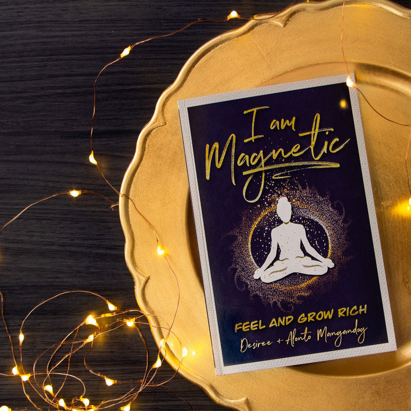 I Am Magnetic, by Desiree de Lunae, sitting on a gold plate with fairy lights.