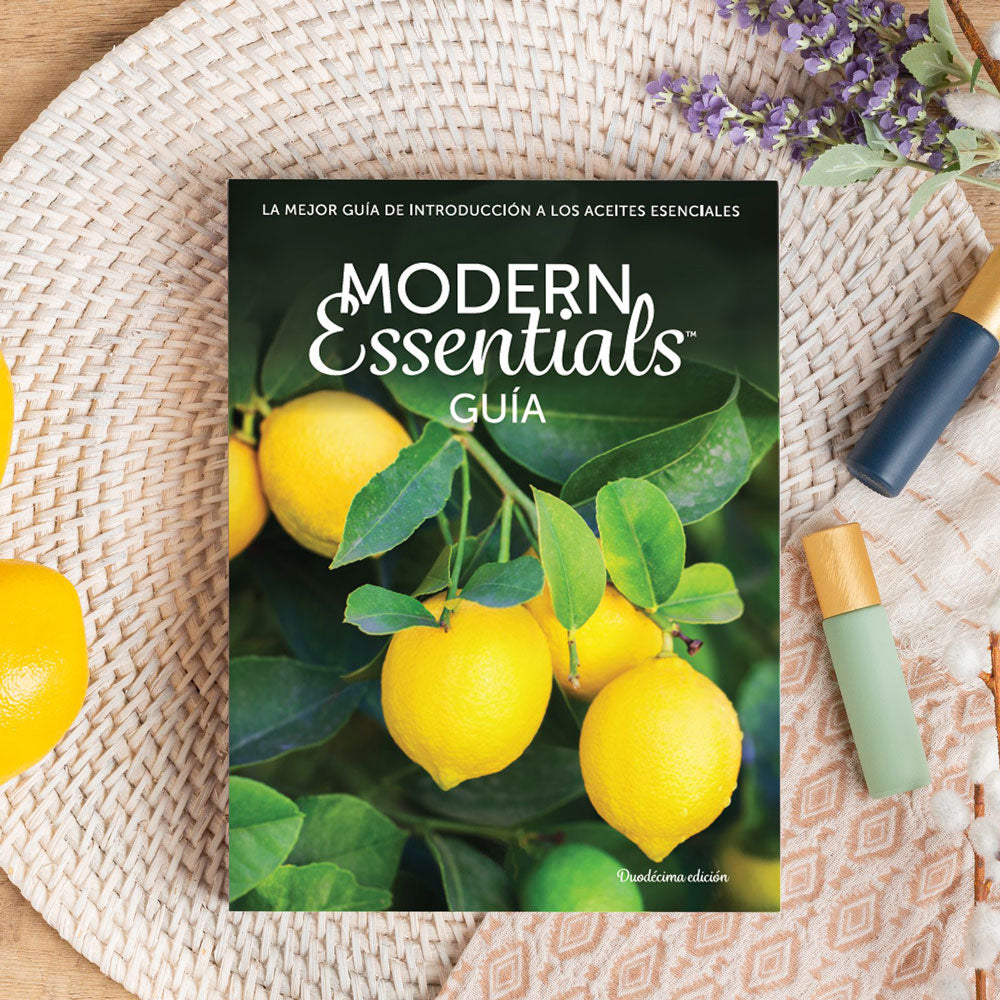 The Modern Essentials Handbook in Spanish (12th Edition) with some roller bottles and lavender.