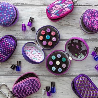 Our cute, little round hard shell and keychain sample cases on a wooden table with sample essential oil vials.