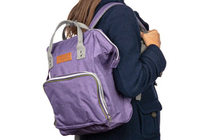 A woman wearing the doTERRA Wellness Advocate Branded Backpack in a purple with olive green accent color.