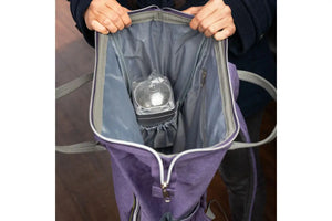 Someone holding open the doTERRA Branded backpack showing how a diffuser fits in the size compartment inside the main pocket.